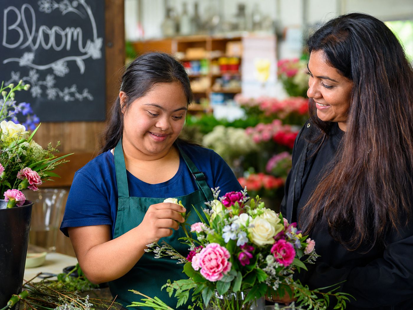 A young woman with Down syndrome arranging flowers in a florist shop.